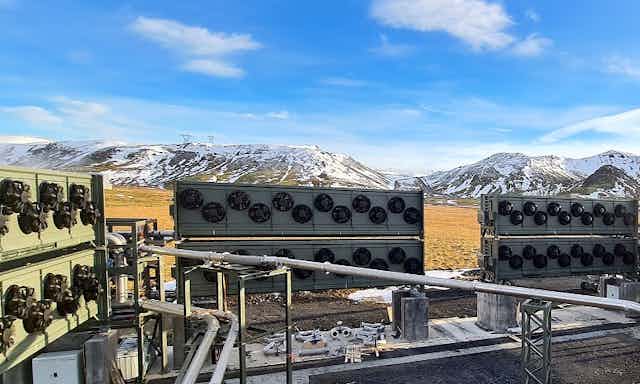 Banks of machinery with fans and mountains with snow in the background. 