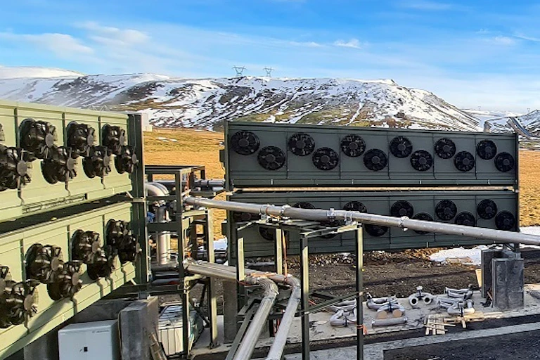 Banks of machinery with fans and mountains with snow in the background.