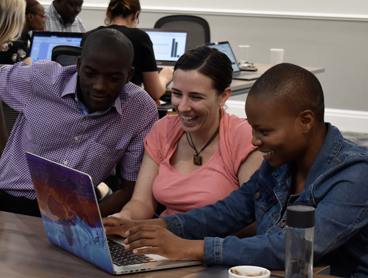 Researchers in the GINGER program looking at laptop together and smiling