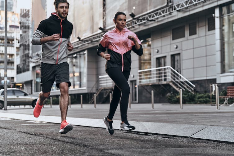 An adult couple go for a run in the city.