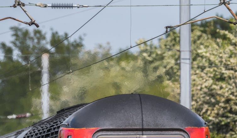 Overhead power lines shimmer above a train in the heat.