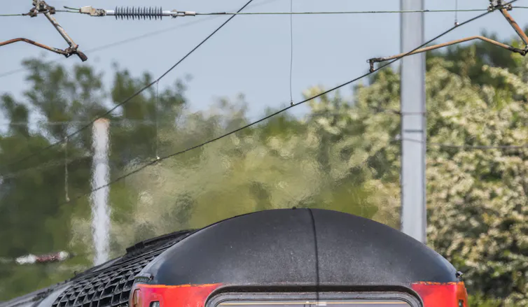 Overhead power lines shimmer above a train in the heat.