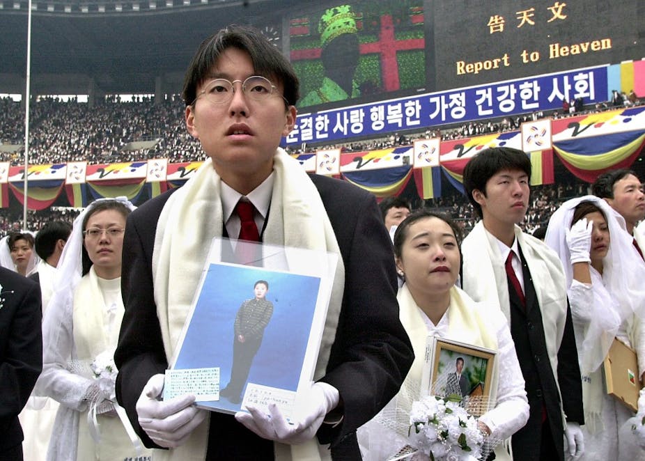 Des jeunes mariés écoutent Sun Myung Moon dans un stade.