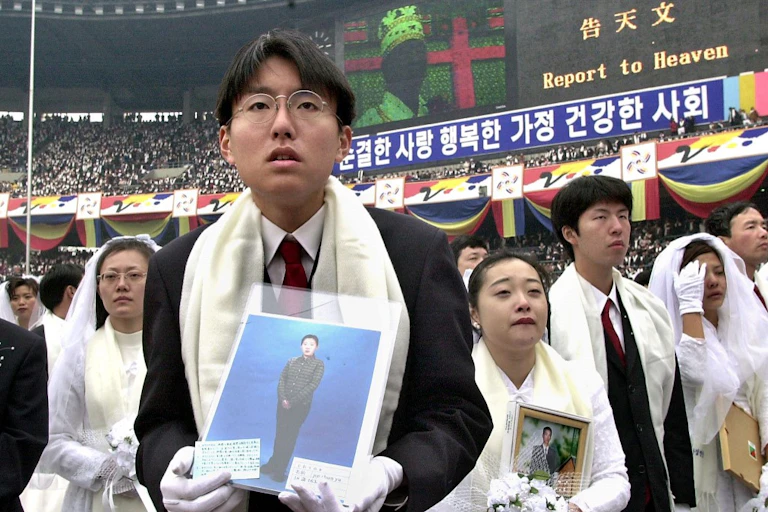 Des jeunes mariés écoutent Sun Myung Moon dans un stade.
