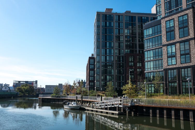 A boat sits by a dock outside a new building along the waterway.