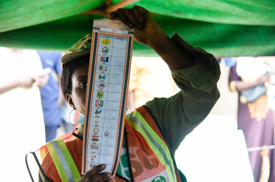A lady in uniform displays ballot paper for election.