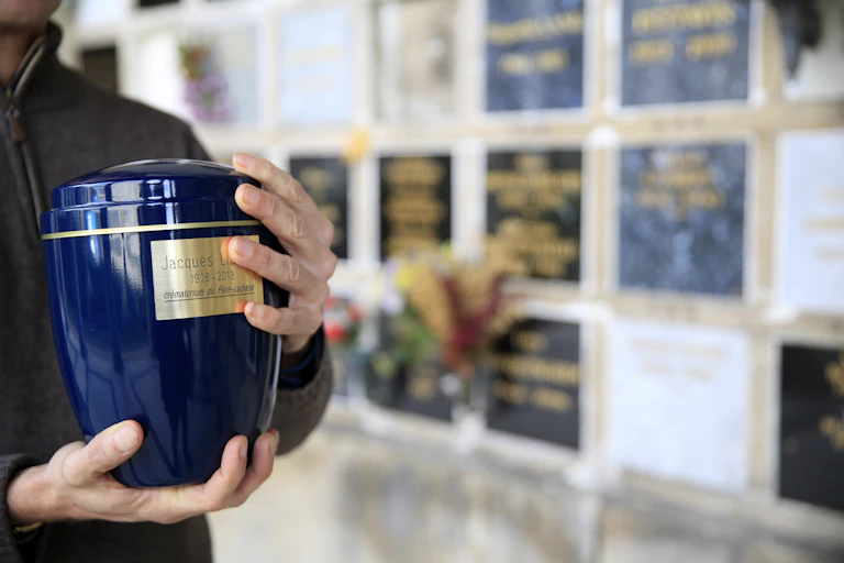 A person holding a blue-colored urn.