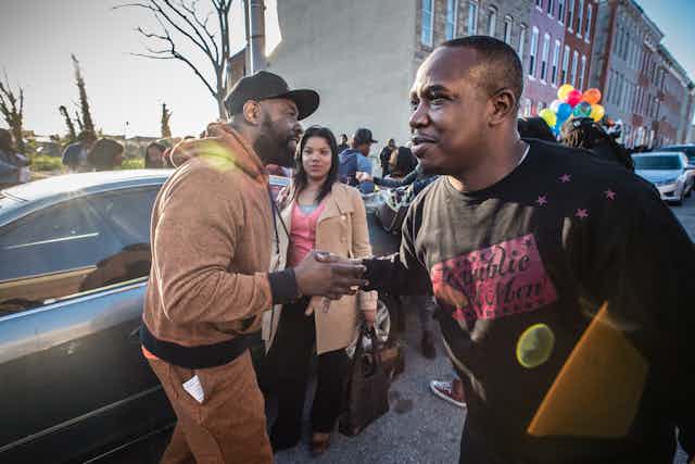 Violence interrupters greet each other on a street in Sandtown