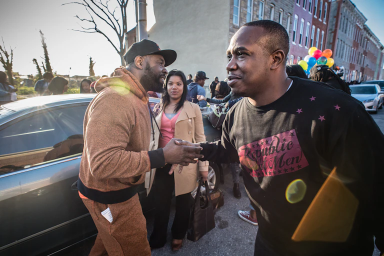 Violence interrupters greet each other on a street in Sandtown