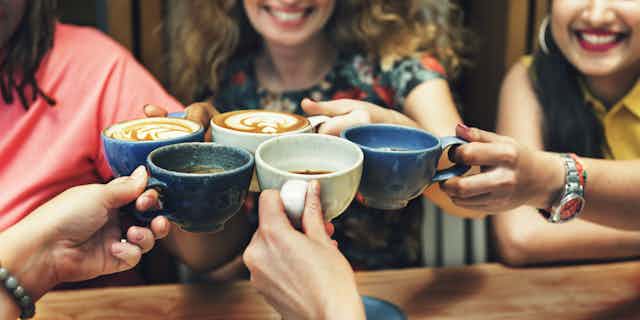 five hands clinking coffee cups together