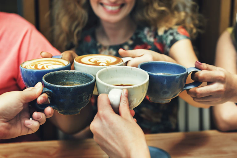 five hands clinking coffee cups together