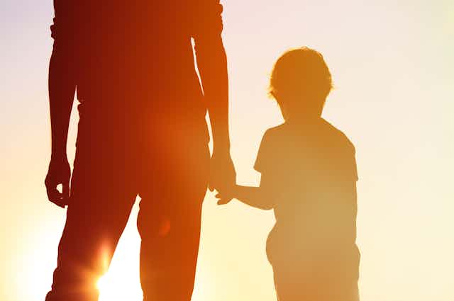 Silhouette of parent and child holding hands