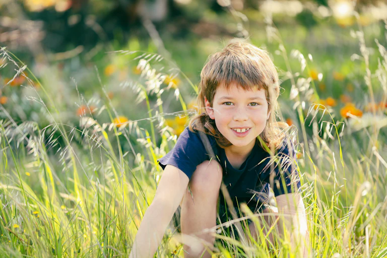 Boy in an overgrown messy area of garden