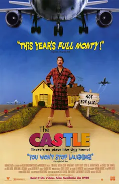 a man stands under a plane, hands on hips, in front of a house