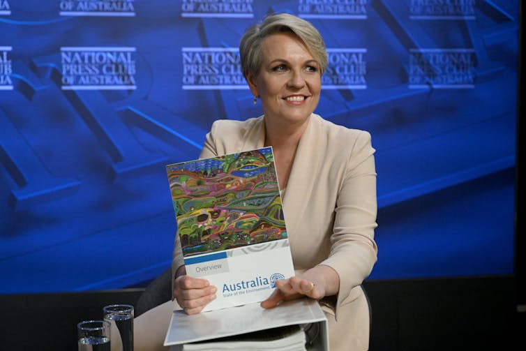 woman with short blonde hair holds report