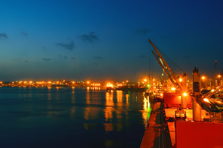 Lights of ships and harbour buildings shining in an evening sky and reflected in water