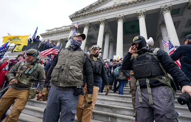 Members of the Oath Keepers, clad in military clothing, stand outside the U.S. Capitol 