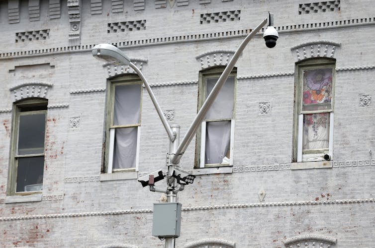 A streetlight post with a second boom with a round black sphere hanging off the end