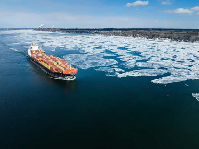 Un porte-conteneurs rempli circule sur une étendue d'eau partiellement glacée