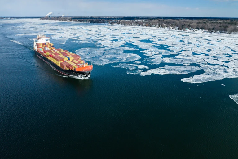 Un porte-conteneurs rempli circule sur une étendue d'eau partiellement glacée