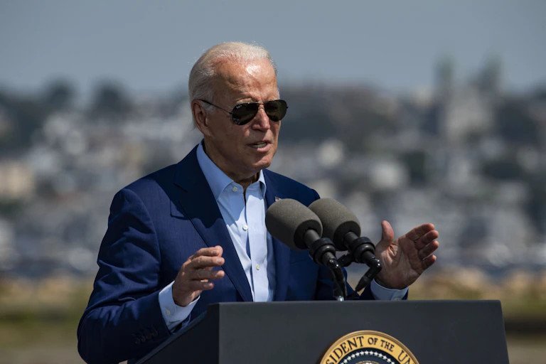 Biden stands at a lectern speaking and gesturing