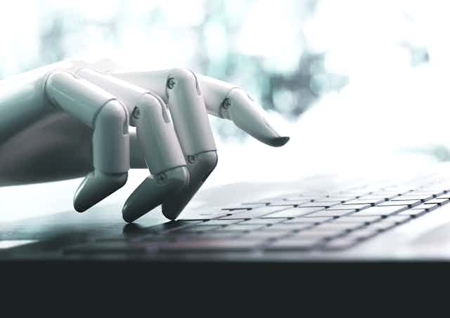 a robot hand hovers over a keyboard