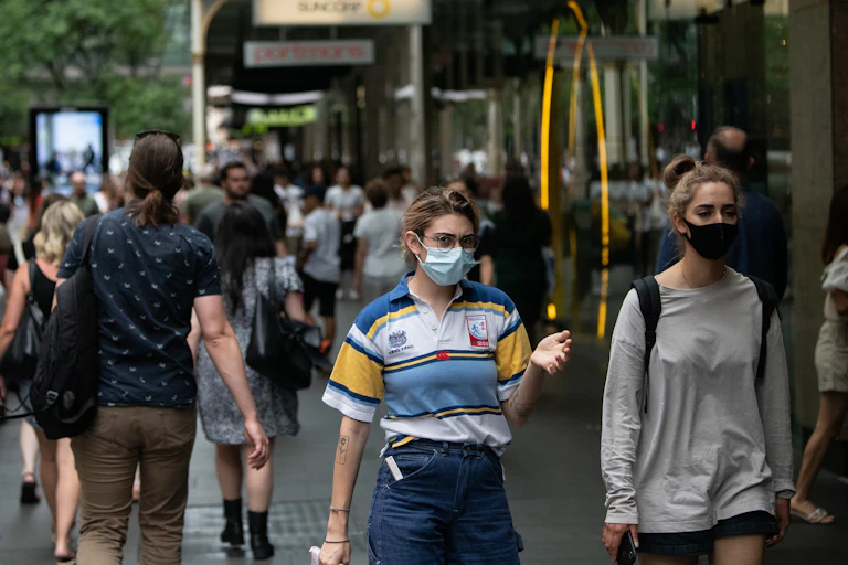 People in masks walk on a busy shopping strip