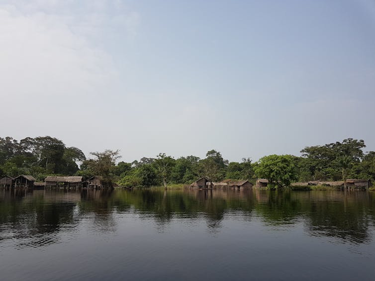 Stilted houses on the far bank of a flooded river.