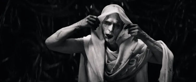 Black and white image of a vampirish-looking pale villain's grimacing face.