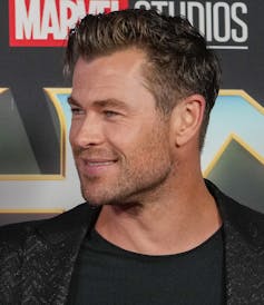 A smiling man seen against a Marvel backdrop.