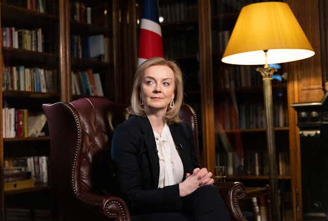 Liz Truss sitting in a library in front of a union flag.