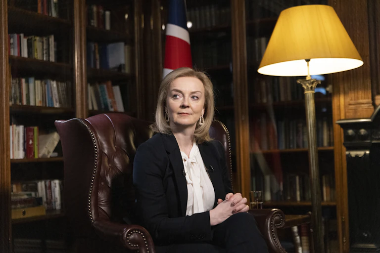 Liz Truss sitting in a library in front of a union flag.