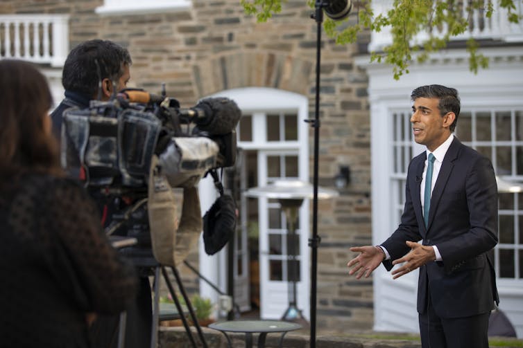 Rishi Sunak talking to a camera on a street.