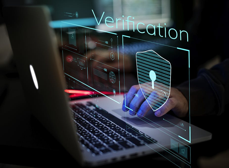 Une main sur un clavier d'ordinateur. L'ambiance est sombre et l'écran affiche le mot vérification.