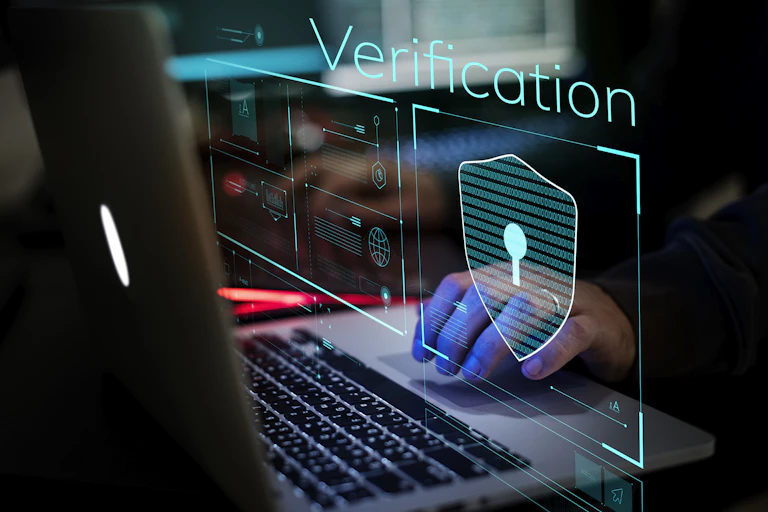 Une main sur un clavier d'ordinateur. L'ambiance est sombre et l'écran affiche le mot vérification.