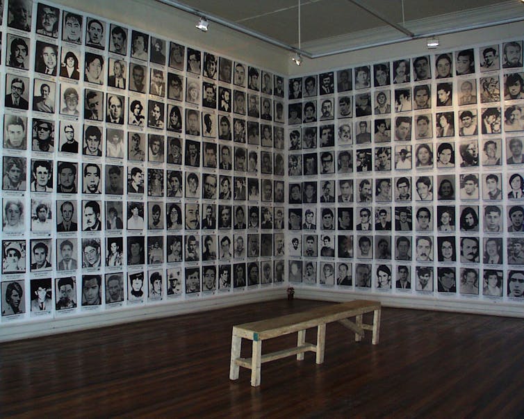 A wall of black and white headshots in a gallery setting.