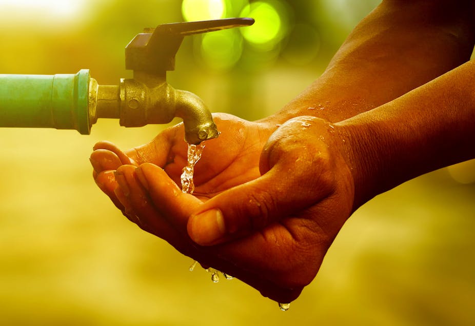 A cupped pair of hands collecting water under an open tap.