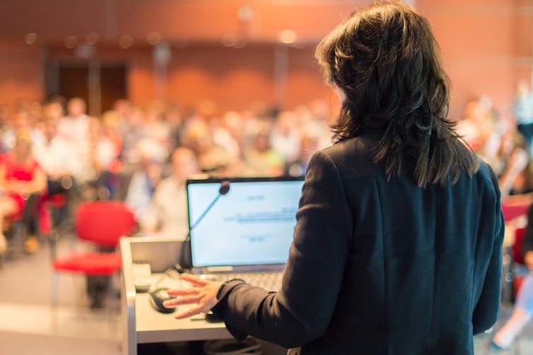 A woman giving a lecture to a room of people