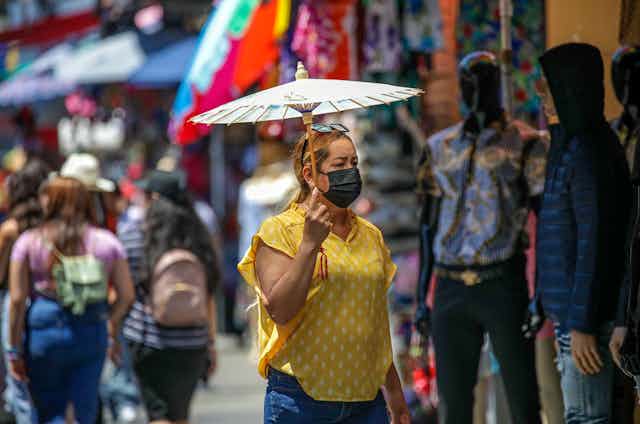 A woman wearing an N95 mask shops in a congested street market.