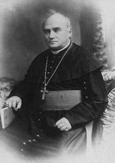 Black and white photo of a man in a white priest's collar.