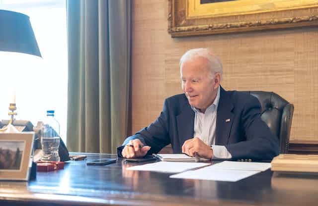 President Joe Biden sitting a desk.