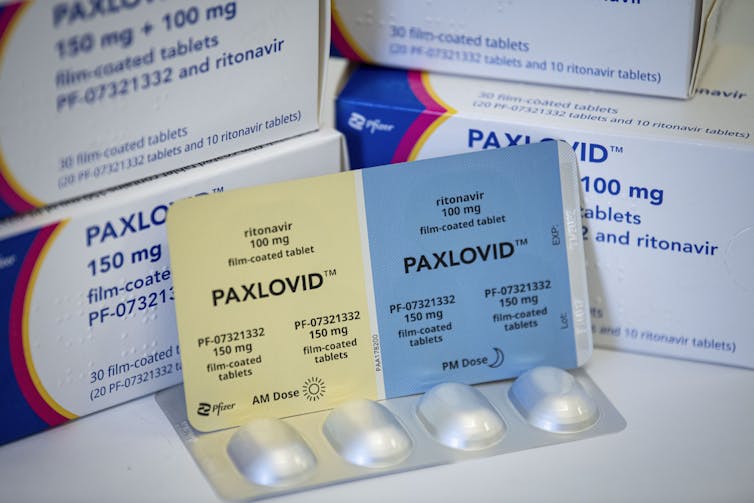 A pill packet labeled with Paxlovid leaning on a box.