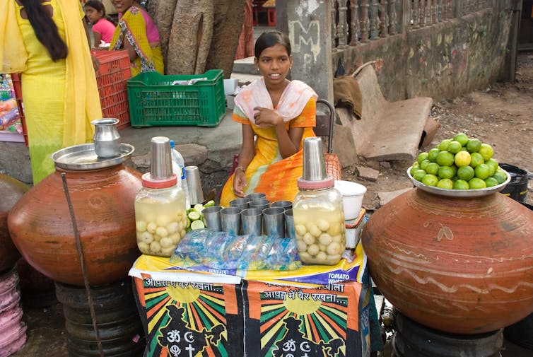 A woman at a stall selling drinks from jars.