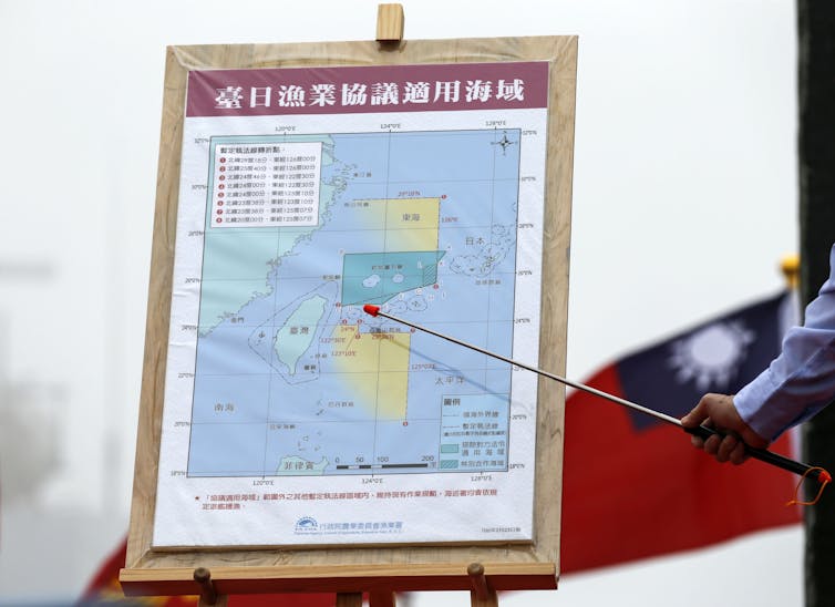 A map of the disputed Diaoyu Islands on an easel. Someone is pointing a stick at the map.
