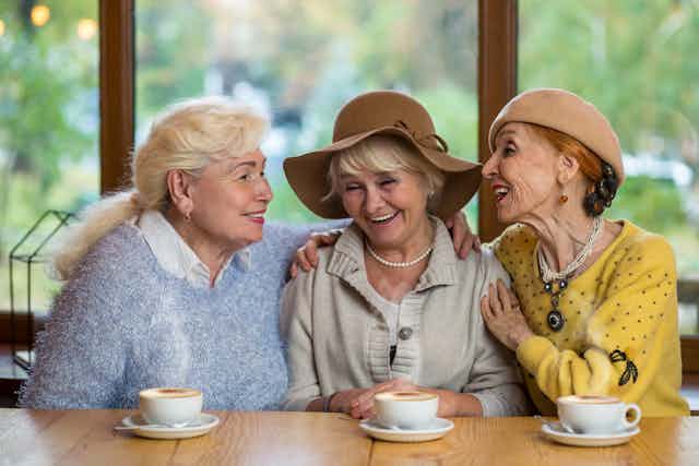 Three older women sit together at a cafe