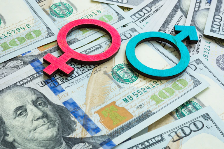Female and male symbols on a background of U.S. hundred dollar bills