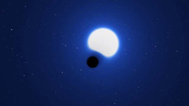 A bright blue star with a black dot in front warping the star.