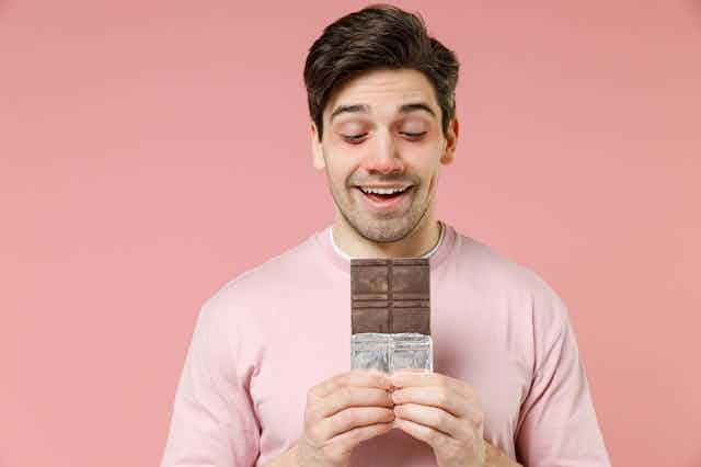 Un hombre con la nariz roja mira con deseo una tableta de chocolate.