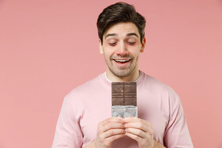 Un hombre con la nariz roja mira con deseo una tableta de chocolate.