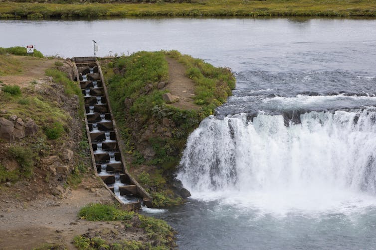 A waterfall is bypassed by a curved, stepped channel of water to the right.